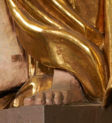 Zdjęcie nr 23: Obie rzeźby są ścięte z tyłu i głęboko drążone. Figury zwrócone są frontalnie z głowami skierowanymi w stronę ołtarza, stoją w kontrapoście. Anioł na lewej bramce unosi prawą rękę w górę, lewą opuszcza w dół. Anioł z prawej bramki prawą rękę kładzie na piersi, lewa zaś jest ugięta i i uniesiona. Anioły mają pociągłe twarze o uwypuklonych brodach, prostych, dużych nosach i szerokich nozdrzach, oczach o łukowatych górnych powiekach i półkolistych łukach brwiowych, pełnych ustach z wydrążonymi kącikami. Włosy opadające na plecy rzeźbione są w grube, falowane i zmierzwione pukle. Postacie ubrane są w tuniki przepasane w talii, przykrywające jedno ramię szerokim rękawem, odsłaniające część torsu i drugą rękę oraz w płaszcze zawinięte w partii ud. Polichromia w partiach ciała naturalistyczna, szaty pozłacane.  
