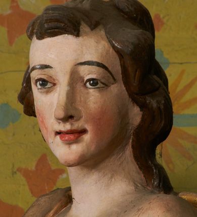 Zdjęcie nr 13: Obie rzeźby są ścięte z tyłu i głęboko drążone. Figury zwrócone są frontalnie z głowami skierowanymi w stronę ołtarza, stoją w kontrapoście. Anioł na lewej bramce unosi prawą rękę w górę, lewą opuszcza w dół. Anioł z prawej bramki prawą rękę kładzie na piersi, lewa zaś jest ugięta i i uniesiona. Anioły mają pociągłe twarze o uwypuklonych brodach, prostych, dużych nosach i szerokich nozdrzach, oczach o łukowatych górnych powiekach i półkolistych łukach brwiowych, pełnych ustach z wydrążonymi kącikami. Włosy opadające na plecy rzeźbione są w grube, falowane i zmierzwione pukle. Postacie ubrane są w tuniki przepasane w talii, przykrywające jedno ramię szerokim rękawem, odsłaniające część torsu i drugą rękę oraz w płaszcze zawinięte w partii ud. Polichromia w partiach ciała naturalistyczna, szaty pozłacane.  
