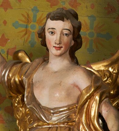 Zdjęcie nr 9: Obie rzeźby są ścięte z tyłu i głęboko drążone. Figury zwrócone są frontalnie z głowami skierowanymi w stronę ołtarza, stoją w kontrapoście. Anioł na lewej bramce unosi prawą rękę w górę, lewą opuszcza w dół. Anioł z prawej bramki prawą rękę kładzie na piersi, lewa zaś jest ugięta i i uniesiona. Anioły mają pociągłe twarze o uwypuklonych brodach, prostych, dużych nosach i szerokich nozdrzach, oczach o łukowatych górnych powiekach i półkolistych łukach brwiowych, pełnych ustach z wydrążonymi kącikami. Włosy opadające na plecy rzeźbione są w grube, falowane i zmierzwione pukle. Postacie ubrane są w tuniki przepasane w talii, przykrywające jedno ramię szerokim rękawem, odsłaniające część torsu i drugą rękę oraz w płaszcze zawinięte w partii ud. Polichromia w partiach ciała naturalistyczna, szaty pozłacane.  
