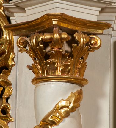 Zdjęcie nr 27: Nastawa architektoniczna, jednoosiowa, dwukondygnacyjna, ustawiona na niewielkim cokole, z dwoma prostopadłościennymi postumentami wydzielonymi po bokach. Ołtarz drewniany, prostopadłościenny, z drewnianą mensą. Antepedium w formie poziomego prostokąta ujętego profilowaną ramą, w polu malowany monogram IHS flankowany gałązkami lilii, u dołu girlanda kwiatowa. W predelli nastawy płycina w formie poziomego prostokąta poszerzonego na krótszych bokach za pomocą nadwieszonych łuków półkolistych, ze sceną modlitwy Chrystusa w Ogrójcu. Pierwsza kondygnacja ujęta parą kolumn stojących na postumentach, o skręconych trzonach dekorowanych ornamentem roślinnym. Podpory dźwigają belkowanie, o pełnych odcinkach nad kolumnami ustawionych pod kątem, z architrawem wyłamującym się schodkowo nad polem środkowym oraz gzymsem przyjmującym formę trzech boków z ośmioboku oraz przerwany, falisty przyczółek. Fryz belkowania ozdobiony jest ornamentem roślinnym, gzyms zaś dekorowany muszlą i zwisami kwiatowymi. Całe pole środkowe wypełnia nisza w kształcie stojącego prostokąta z wciętymi narożami, ujęta ramą ozdobioną ornamentem roślinnym, wewnątrz znajduje się rzeźbiarska grupa Ukrzyżowania na tle malowanego pejzażu. Pierwsza kondygnacja ujęta jest uszami utworzonymi z suchego akantu, w ich dolnej części postumenty dla figur św. Walentego i św. Jana Ewangelisty. Druga kondygnacja jest węższa od poprzedniej, flankowana parą ustawionych lekko pod kątem pilastrów dźwigających gzyms, dekorowanych w partii trzonów kampanulami. W polu obraz ze św. Wawrzyńcem w formie pionowego owalu w profilowanej ramie. Całość zwieńczona okiem Opatrzności na tle obłoków w glorii promienistej. Na belkowaniu niewielkie figury aniołów. Druga kondygnacja ujęta jest pionowymi rzędami kampanul. Struktura polichromowana w kolorze białym, z pozłacanymi profilami i elementami ornamentyki oraz srebrzonymi detalami. 