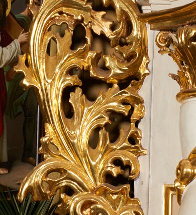 Zdjęcie nr 8: Nastawa architektoniczna, jednoosiowa, dwukondygnacyjna, ustawiona na niewielkim cokole, z dwoma prostopadłościennymi postumentami wydzielonymi po bokach. Ołtarz drewniany, prostopadłościenny, z drewnianą mensą. Antepedium w formie poziomego prostokąta ujętego profilowaną ramą, w polu malowany monogram IHS flankowany gałązkami lilii, u dołu girlanda kwiatowa. W predelli nastawy płycina w formie poziomego prostokąta poszerzonego na krótszych bokach za pomocą nadwieszonych łuków półkolistych, ze sceną modlitwy Chrystusa w Ogrójcu. Pierwsza kondygnacja ujęta parą kolumn stojących na postumentach, o skręconych trzonach dekorowanych ornamentem roślinnym. Podpory dźwigają belkowanie, o pełnych odcinkach nad kolumnami ustawionych pod kątem, z architrawem wyłamującym się schodkowo nad polem środkowym oraz gzymsem przyjmującym formę trzech boków z ośmioboku oraz przerwany, falisty przyczółek. Fryz belkowania ozdobiony jest ornamentem roślinnym, gzyms zaś dekorowany muszlą i zwisami kwiatowymi. Całe pole środkowe wypełnia nisza w kształcie stojącego prostokąta z wciętymi narożami, ujęta ramą ozdobioną ornamentem roślinnym, wewnątrz znajduje się rzeźbiarska grupa Ukrzyżowania na tle malowanego pejzażu. Pierwsza kondygnacja ujęta jest uszami utworzonymi z suchego akantu, w ich dolnej części postumenty dla figur św. Walentego i św. Jana Ewangelisty. Druga kondygnacja jest węższa od poprzedniej, flankowana parą ustawionych lekko pod kątem pilastrów dźwigających gzyms, dekorowanych w partii trzonów kampanulami. W polu obraz ze św. Wawrzyńcem w formie pionowego owalu w profilowanej ramie. Całość zwieńczona okiem Opatrzności na tle obłoków w glorii promienistej. Na belkowaniu niewielkie figury aniołów. Druga kondygnacja ujęta jest pionowymi rzędami kampanul. Struktura polichromowana w kolorze białym, z pozłacanymi profilami i elementami ornamentyki oraz srebrzonymi detalami. 