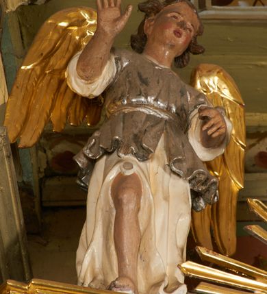 Zdjęcie nr 16: Nastawa architektoniczna, jednoosiowa, dwukondygnacyjna, ustawiona na niewielkim cokole, z dwoma prostopadłościennymi postumentami wydzielonymi po bokach. Ołtarz drewniany, prostopadłościenny, z drewnianą mensą. Antepedium w formie poziomego prostokąta ujętego profilowaną ramą, w polu malowany monogram IHS flankowany gałązkami lilii, u dołu girlanda kwiatowa. W predelli nastawy płycina w formie poziomego prostokąta poszerzonego na krótszych bokach za pomocą nadwieszonych łuków półkolistych, ze sceną modlitwy Chrystusa w Ogrójcu. Pierwsza kondygnacja ujęta parą kolumn stojących na postumentach, o skręconych trzonach dekorowanych ornamentem roślinnym. Podpory dźwigają belkowanie, o pełnych odcinkach nad kolumnami ustawionych pod kątem, z architrawem wyłamującym się schodkowo nad polem środkowym oraz gzymsem przyjmującym formę trzech boków z ośmioboku oraz przerwany, falisty przyczółek. Fryz belkowania ozdobiony jest ornamentem roślinnym, gzyms zaś dekorowany muszlą i zwisami kwiatowymi. Całe pole środkowe wypełnia nisza w kształcie stojącego prostokąta z wciętymi narożami, ujęta ramą ozdobioną ornamentem roślinnym, wewnątrz znajduje się rzeźbiarska grupa Ukrzyżowania na tle malowanego pejzażu. Pierwsza kondygnacja ujęta jest uszami utworzonymi z suchego akantu, w ich dolnej części postumenty dla figur św. Walentego i św. Jana Ewangelisty. Druga kondygnacja jest węższa od poprzedniej, flankowana parą ustawionych lekko pod kątem pilastrów dźwigających gzyms, dekorowanych w partii trzonów kampanulami. W polu obraz ze św. Wawrzyńcem w formie pionowego owalu w profilowanej ramie. Całość zwieńczona okiem Opatrzności na tle obłoków w glorii promienistej. Na belkowaniu niewielkie figury aniołów. Druga kondygnacja ujęta jest pionowymi rzędami kampanul. Struktura polichromowana w kolorze białym, z pozłacanymi profilami i elementami ornamentyki oraz srebrzonymi detalami. 