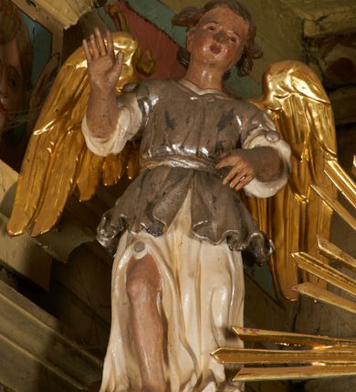 Zdjęcie nr 14: Nastawa architektoniczna, jednoosiowa, dwukondygnacyjna, ustawiona na niewielkim cokole, z dwoma prostopadłościennymi postumentami wydzielonymi po bokach. Ołtarz drewniany, prostopadłościenny, z drewnianą mensą. Antepedium w formie poziomego prostokąta ujętego profilowaną ramą, w polu malowany monogram IHS flankowany gałązkami lilii, u dołu girlanda kwiatowa. W predelli nastawy płycina w formie poziomego prostokąta poszerzonego na krótszych bokach za pomocą nadwieszonych łuków półkolistych, ze sceną modlitwy Chrystusa w Ogrójcu. Pierwsza kondygnacja ujęta parą kolumn stojących na postumentach, o skręconych trzonach dekorowanych ornamentem roślinnym. Podpory dźwigają belkowanie, o pełnych odcinkach nad kolumnami ustawionych pod kątem, z architrawem wyłamującym się schodkowo nad polem środkowym oraz gzymsem przyjmującym formę trzech boków z ośmioboku oraz przerwany, falisty przyczółek. Fryz belkowania ozdobiony jest ornamentem roślinnym, gzyms zaś dekorowany muszlą i zwisami kwiatowymi. Całe pole środkowe wypełnia nisza w kształcie stojącego prostokąta z wciętymi narożami, ujęta ramą ozdobioną ornamentem roślinnym, wewnątrz znajduje się rzeźbiarska grupa Ukrzyżowania na tle malowanego pejzażu. Pierwsza kondygnacja ujęta jest uszami utworzonymi z suchego akantu, w ich dolnej części postumenty dla figur św. Walentego i św. Jana Ewangelisty. Druga kondygnacja jest węższa od poprzedniej, flankowana parą ustawionych lekko pod kątem pilastrów dźwigających gzyms, dekorowanych w partii trzonów kampanulami. W polu obraz ze św. Wawrzyńcem w formie pionowego owalu w profilowanej ramie. Całość zwieńczona okiem Opatrzności na tle obłoków w glorii promienistej. Na belkowaniu niewielkie figury aniołów. Druga kondygnacja ujęta jest pionowymi rzędami kampanul. Struktura polichromowana w kolorze białym, z pozłacanymi profilami i elementami ornamentyki oraz srebrzonymi detalami. 