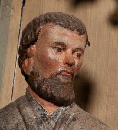 Zdjęcie nr 8: Święty został ukazany frontalnie, w wykroku, z głową skierowaną w lewo, w wykroku, lewą ręką podtrzymuje otwartą księgę, prawą unosi w geście błogosławieństwa. Jego twarz jest pociągła, o małych oczach, krótkim nosie i wąskich ustach, okolona brodą i krótkimi włosami. Ubrany jest w białą albę i posrebrzany ornat. Przy jego lewej nodze półpostać mężczyzny, który prawą ręką trzyma szatę świętego, ubrany jest w białą, przepasaną w talii tunikę. Polichromia ciała naturalistyczna, ornat posrebrzany.

