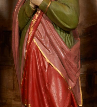 Zdjęcie nr 5: Rzeźbiona grupa Ukrzyżowania znajduje się we wnęce, ujętej ramą, zdobioną stylizowanymi liśćmi, na niewysokim podeście. Umarły Chrystus przybity jest do drzewa krzyża trzema gwoździami, ukazany frontalnie, z głową lekko opadającą na prawe ramię. Ciało w niewielkim zwisie, z ramionami układającymi się w łuk, o delikatnym modelunku mięśni. Chrystus ma pociągłą twarz, którą okalają broda i wąsy. Włosy swobodnie opadają na ramiona. Na głowie korona cierniowa. Jego biodra przepasane są białym perizonium, sięgającym do połowy ud, zdobionym złotą lamówką, zawiązanym na lewym boku ze zwisem tkaniny. Po lewej stronie krzyża stoi Matka Boska, obrócona ku niemu w trzech czwartych, z rękami skrzyżowanymi na piersiach. Twarz ma pociągłą, z zamkniętymi oczami. Maria odziana jest w czerwoną suknię, niebieski płaszcz, zdobiony złotą bordiurą i geometrycznym ornamentem, na głowie ma biały welon, owinięty wokół szyi. Po prawej stronie krzyża znajduje się postać św. Jana Ewangelisty, również zwróconego w trzech czwartych ku krzyżowi, przedstawionego w kontrapoście, z rękami skrzyżowanymi na piersiach. Jego głowa jest lekko uniesiona do góry, twarz jest pociągła. Włosy swobodnie opadające na ramiona. Święty odziany jest w zieloną tunikę, zdobioną złotą lamówką oraz czerwony płaszcz, zarzucony na prawe ramię i podtrzymywany z przodu. Grupa Ukrzyżowania ukazana została na malowanym monochromatycznie tle we wnęce przedstawiającym skalisty pejzaż. Figury w partiach ciała polichromowane są naturalistycznie, detale szat pozłacane. 