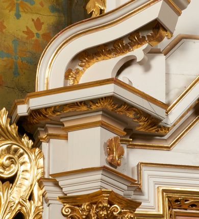 Zdjęcie nr 12: Nastawa ołtarzowa architektoniczna, jednoosiowa, dwukondygnacyjna, ustawiona na niewielkim cokole, z dwoma prostopadłościennymi postumentami wydzielonymi po bokach. Ołtarz drewniany, prostopadłościenny, z drewnianą mensą. Antepedium w formie poziomego prostokąta ujętego profilowaną ramą, w polu malowany monogram Marii, flankowany różanymi gałązkami. W predelli nastawy znajduje się płycina w formie poziomego prostokąta poszerzonego na krótszych bokach za pomocą nadwieszonych łuków półkolistych, ze sceną Zwiastowania. 
Pierwsza kondygnacja ujęta jest parą kolumn stojących na postumentach, o skręconych trzonach dekorowanych ornamentem roślinnym. Podpory dźwigają belkowanie, którego pełne odcinki nad kolumnami ustawione są pod kątem, architraw nad polem środkowym wyłamuje się schodkowo, a gzyms przyjmuje formę trzech boków z ośmioboku. Wyżej widoczny oraz przerwany falisty przyczółek. Fryz belkowania ozdobiony jest palmetami oraz dekoracją roślinną, gzyms dekorowany palmetą. Całe pole środkowe wypełnia obraz Matki Boskiej Różańcowej ze św. Dominikiem i św. Katarzyną Sieneńską w formie pionowego prostokąta z wciętymi narożami, w ramie ozdobionej stylizowanym ornamentem. Pierwsza kondygnacja ujęta jest częściowo ażurowymi uszami utworzonymi z akantu i karbowanej wstęgi. Druga kondygnacja jest węższa, flankowana parą ustawionych lekko pod kątem pilastrów, dekorowanych w partii trzonów kampanulami, dźwigających gzyms,. W polu obraz Objawienia Matki Boskiej w Lourdes w formie pionowego owalu w profilowanej ramie, flankowany kampanulami. Całość zwieńczona medalionem w glorii z monogramem Marii. Na belkowaniu niewielkie figury św. Barbary i św. Michała Archanioła. Druga kondygnacja ujęta jest pionowymi rzędami kampanul. Struktura polichromowana w kolorze białym z pozłacanymi profilami i elementami ornamentyki. 


