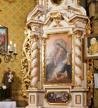 Zdjęcie nr 1: Nastawa ołtarzowa architektoniczna, jednoosiowa, dwukondygnacyjna, ustawiona na niewielkim cokole, z dwoma prostopadłościennymi postumentami wydzielonymi po bokach. Ołtarz drewniany, prostopadłościenny, z drewnianą mensą. Antepedium w formie poziomego prostokąta ujętego profilowaną ramą, w polu malowany monogram Marii, flankowany różanymi gałązkami. W predelli nastawy znajduje się płycina w formie poziomego prostokąta poszerzonego na krótszych bokach za pomocą nadwieszonych łuków półkolistych, ze sceną Zwiastowania. 
Pierwsza kondygnacja ujęta jest parą kolumn stojących na postumentach, o skręconych trzonach dekorowanych ornamentem roślinnym. Podpory dźwigają belkowanie, którego pełne odcinki nad kolumnami ustawione są pod kątem, architraw nad polem środkowym wyłamuje się schodkowo, a gzyms przyjmuje formę trzech boków z ośmioboku. Wyżej widoczny oraz przerwany falisty przyczółek. Fryz belkowania ozdobiony jest palmetami oraz dekoracją roślinną, gzyms dekorowany palmetą. Całe pole środkowe wypełnia obraz Matki Boskiej Różańcowej ze św. Dominikiem i św. Katarzyną Sieneńską w formie pionowego prostokąta z wciętymi narożami, w ramie ozdobionej stylizowanym ornamentem. Pierwsza kondygnacja ujęta jest częściowo ażurowymi uszami utworzonymi z akantu i karbowanej wstęgi. Druga kondygnacja jest węższa, flankowana parą ustawionych lekko pod kątem pilastrów, dekorowanych w partii trzonów kampanulami, dźwigających gzyms,. W polu obraz Objawienia Matki Boskiej w Lourdes w formie pionowego owalu w profilowanej ramie, flankowany kampanulami. Całość zwieńczona medalionem w glorii z monogramem Marii. Na belkowaniu niewielkie figury św. Barbary i św. Michała Archanioła. Druga kondygnacja ujęta jest pionowymi rzędami kampanul. Struktura polichromowana w kolorze białym z pozłacanymi profilami i elementami ornamentyki. 


