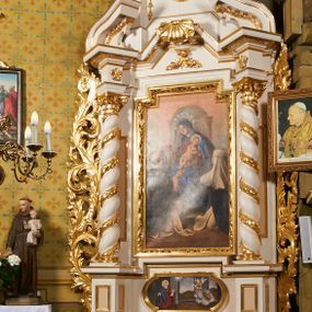 Zdjęcie nr 1: Nastawa ołtarzowa architektoniczna, jednoosiowa, dwukondygnacyjna, ustawiona na niewielkim cokole, z dwoma prostopadłościennymi postumentami wydzielonymi po bokach. Ołtarz drewniany, prostopadłościenny, z drewnianą mensą. Antepedium w formie poziomego prostokąta ujętego profilowaną ramą, w polu malowany monogram Marii, flankowany różanymi gałązkami. W predelli nastawy znajduje się płycina w formie poziomego prostokąta poszerzonego na krótszych bokach za pomocą nadwieszonych łuków półkolistych, ze sceną Zwiastowania. 
Pierwsza kondygnacja ujęta jest parą kolumn stojących na postumentach, o skręconych trzonach dekorowanych ornamentem roślinnym. Podpory dźwigają belkowanie, którego pełne odcinki nad kolumnami ustawione są pod kątem, architraw nad polem środkowym wyłamuje się schodkowo, a gzyms przyjmuje formę trzech boków z ośmioboku. Wyżej widoczny oraz przerwany falisty przyczółek. Fryz belkowania ozdobiony jest palmetami oraz dekoracją roślinną, gzyms dekorowany palmetą. Całe pole środkowe wypełnia obraz Matki Boskiej Różańcowej ze św. Dominikiem i św. Katarzyną Sieneńską w formie pionowego prostokąta z wciętymi narożami, w ramie ozdobionej stylizowanym ornamentem. Pierwsza kondygnacja ujęta jest częściowo ażurowymi uszami utworzonymi z akantu i karbowanej wstęgi. Druga kondygnacja jest węższa, flankowana parą ustawionych lekko pod kątem pilastrów, dekorowanych w partii trzonów kampanulami, dźwigających gzyms,. W polu obraz Objawienia Matki Boskiej w Lourdes w formie pionowego owalu w profilowanej ramie, flankowany kampanulami. Całość zwieńczona medalionem w glorii z monogramem Marii. Na belkowaniu niewielkie figury św. Barbary i św. Michała Archanioła. Druga kondygnacja ujęta jest pionowymi rzędami kampanul. Struktura polichromowana w kolorze białym z pozłacanymi profilami i elementami ornamentyki. 


