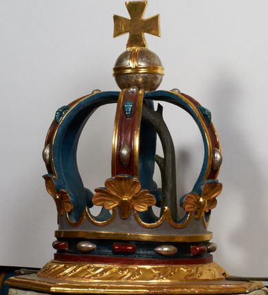 Zdjęcie nr 4: Kamienna chrzcielnica stoi na niewysokiej, kamiennej podstawie na planie koła. Jej stopa jest na planie ośmioboku, u dołu z pionowo ściętym cokołem i zwęża się stożkowato ku górze. Nodus jest spłaszczony, ośmioboczny. Czara ośmioboczna, dwustrefowa, u dołu zaokrąglona, u góry prosto ścięta, nadwieszona, w górnej strefie pola dekorowane są motywem trójlistnego maswerku. Wewnątrz czary znajduje się metalowa misa. Drewniana pokrywa przyjmuje kształt korony zamkniętej sześcioma kabłąkami z kulą i krzyżem umieszczonymi na szczycie. Polichromowana w kolorach zielonym i czerwonym, wewnątrz na niebiesko, obręcz korony i kula posrebrzane, detale i brzegi pozłacane.