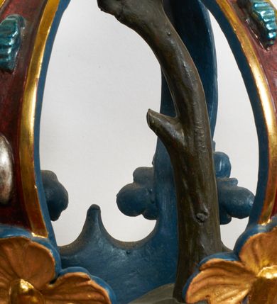 Zdjęcie nr 5: Kamienna chrzcielnica stoi na niewysokiej, kamiennej podstawie na planie koła. Jej stopa jest na planie ośmioboku, u dołu z pionowo ściętym cokołem i zwęża się stożkowato ku górze. Nodus jest spłaszczony, ośmioboczny. Czara ośmioboczna, dwustrefowa, u dołu zaokrąglona, u góry prosto ścięta, nadwieszona, w górnej strefie pola dekorowane są motywem trójlistnego maswerku. Wewnątrz czary znajduje się metalowa misa. Drewniana pokrywa przyjmuje kształt korony zamkniętej sześcioma kabłąkami z kulą i krzyżem umieszczonymi na szczycie. Polichromowana w kolorach zielonym i czerwonym, wewnątrz na niebiesko, obręcz korony i kula posrebrzane, detale i brzegi pozłacane.