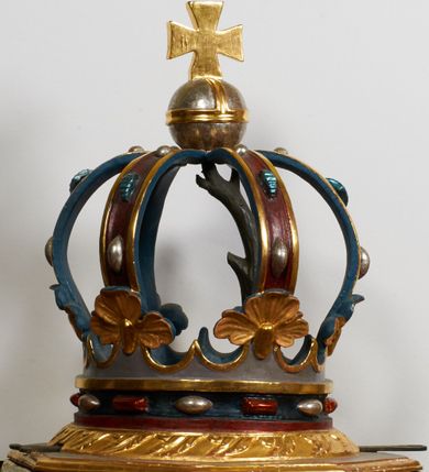 Zdjęcie nr 3: Kamienna chrzcielnica stoi na niewysokiej, kamiennej podstawie na planie koła. Jej stopa jest na planie ośmioboku, u dołu z pionowo ściętym cokołem i zwęża się stożkowato ku górze. Nodus jest spłaszczony, ośmioboczny. Czara ośmioboczna, dwustrefowa, u dołu zaokrąglona, u góry prosto ścięta, nadwieszona, w górnej strefie pola dekorowane są motywem trójlistnego maswerku. Wewnątrz czary znajduje się metalowa misa. Drewniana pokrywa przyjmuje kształt korony zamkniętej sześcioma kabłąkami z kulą i krzyżem umieszczonymi na szczycie. Polichromowana w kolorach zielonym i czerwonym, wewnątrz na niebiesko, obręcz korony i kula posrebrzane, detale i brzegi pozłacane.