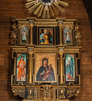 Zdjęcie nr 1: Ołtarz przyścienny, architektoniczny, trójosiowy, dwukondygnacjowy. Nastawa ołtarzowa ustawiona na prostopadłościennym stole ołtarzowym, zasłanym czerwonym materiałem. Predella na niskim cokoliku w formie półwałku, zamknięta u góry puklowanym gzymsem. W osi środkowej wmontowane tabernakulum ozdobione bujną, płaskorzeźbioną winną latoroślą. Po jego bokach ścianki z lustrami, flankowane parą spiralnie skręconych laskowań. W osiach bocznych predelli płyciny o uszatych narożach, w polu których znajdują się pilastry hermowe ze skierowanymi na wprost kobiecymi głowami. Na skrajach predelli konsolki, bogato dekorowane wicią, zawijającą się w wolutki, zdobioną perełkowaniem; na brzegu konsolki skierowana ku dołowi głowa. Pierwsza kondygnacja artykułowana parą kolumn o korynckich kapitelach, wspierających niepełne belkowanie, wyłamane na ich osi. W polu głównym obraz Matki Boskiej z Dzieciątkiem, w osiach bocznych wmontowane skrzydła tryptyku z przedstawieniami: Ecce Homo po lewej stronie oraz Matki Boskiej Bolesnej po prawej stronie. Każda z osi ujęta na brzegach obramowaniem w kształcie stojącego prostokąta o uszatych narożnikach. Fryz dekorowany symetryczną wicią roślinną, nad kolumnami srebrzone rauty. Druga kondygnacja mniejsza, flankowana analogicznymi kolumnami, wspierającymi podobne belkowanie. W polu głównym obraz św. Andrzeja w kształcie stojącego prostokąta. W lewej osi bocznej obraz św. Wojciecha, a w prawej św. Stanisława, oba zamknięte łukiem nadwieszonym. Po bokach kondygnacji uszy o wykroju okuciowym, zdobione wicią oraz podwieszonymi girlandami z owocami winogron. Nad ołtarzem zamocowana promienista gloria, w polu której znajduje się oko Opatrzności otoczone wieńcem z obłoków oraz sześcioma skrzydlatymi główkami anielskimi. Struktura malowana na kolor czarny, kolumny i ornamentyka złocone, detale srebrzone.