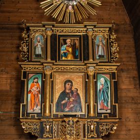 Zdjęcie nr 1: Ołtarz przyścienny, architektoniczny, trójosiowy, dwukondygnacjowy. Nastawa ołtarzowa ustawiona na prostopadłościennym stole ołtarzowym, zasłanym czerwonym materiałem. Predella na niskim cokoliku w formie półwałku, zamknięta u góry puklowanym gzymsem. W osi środkowej wmontowane tabernakulum ozdobione bujną, płaskorzeźbioną winną latoroślą. Po jego bokach ścianki z lustrami, flankowane parą spiralnie skręconych laskowań. W osiach bocznych predelli płyciny o uszatych narożach, w polu których znajdują się pilastry hermowe ze skierowanymi na wprost kobiecymi głowami. Na skrajach predelli konsolki, bogato dekorowane wicią, zawijającą się w wolutki, zdobioną perełkowaniem; na brzegu konsolki skierowana ku dołowi głowa. Pierwsza kondygnacja artykułowana parą kolumn o korynckich kapitelach, wspierających niepełne belkowanie, wyłamane na ich osi. W polu głównym obraz Matki Boskiej z Dzieciątkiem, w osiach bocznych wmontowane skrzydła tryptyku z przedstawieniami: Ecce Homo po lewej stronie oraz Matki Boskiej Bolesnej po prawej stronie. Każda z osi ujęta na brzegach obramowaniem w kształcie stojącego prostokąta o uszatych narożnikach. Fryz dekorowany symetryczną wicią roślinną, nad kolumnami srebrzone rauty. Druga kondygnacja mniejsza, flankowana analogicznymi kolumnami, wspierającymi podobne belkowanie. W polu głównym obraz św. Andrzeja w kształcie stojącego prostokąta. W lewej osi bocznej obraz św. Wojciecha, a w prawej św. Stanisława, oba zamknięte łukiem nadwieszonym. Po bokach kondygnacji uszy o wykroju okuciowym, zdobione wicią oraz podwieszonymi girlandami z owocami winogron. Nad ołtarzem zamocowana promienista gloria, w polu której znajduje się oko Opatrzności otoczone wieńcem z obłoków oraz sześcioma skrzydlatymi główkami anielskimi. Struktura malowana na kolor czarny, kolumny i ornamentyka złocone, detale srebrzone.