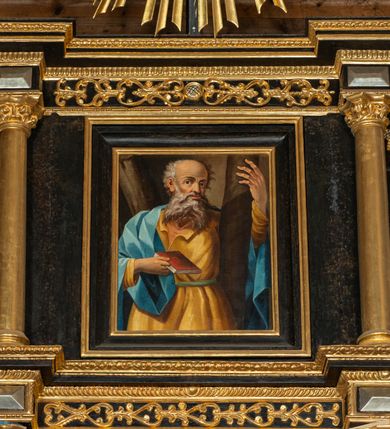 Zdjęcie nr 13: Ołtarz przyścienny, architektoniczny, trójosiowy, dwukondygnacjowy. Nastawa ołtarzowa ustawiona na prostopadłościennym stole ołtarzowym, zasłanym czerwonym materiałem. Predella na niskim cokoliku w formie półwałku, zamknięta u góry puklowanym gzymsem. W osi środkowej wmontowane tabernakulum ozdobione bujną, płaskorzeźbioną winną latoroślą. Po jego bokach ścianki z lustrami, flankowane parą spiralnie skręconych laskowań. W osiach bocznych predelli płyciny o uszatych narożach, w polu których znajdują się pilastry hermowe ze skierowanymi na wprost kobiecymi głowami. Na skrajach predelli konsolki, bogato dekorowane wicią, zawijającą się w wolutki, zdobioną perełkowaniem; na brzegu konsolki skierowana ku dołowi głowa. Pierwsza kondygnacja artykułowana parą kolumn o korynckich kapitelach, wspierających niepełne belkowanie, wyłamane na ich osi. W polu głównym obraz Matki Boskiej z Dzieciątkiem, w osiach bocznych wmontowane skrzydła tryptyku z przedstawieniami: Ecce Homo po lewej stronie oraz Matki Boskiej Bolesnej po prawej stronie. Każda z osi ujęta na brzegach obramowaniem w kształcie stojącego prostokąta o uszatych narożnikach. Fryz dekorowany symetryczną wicią roślinną, nad kolumnami srebrzone rauty. Druga kondygnacja mniejsza, flankowana analogicznymi kolumnami, wspierającymi podobne belkowanie. W polu głównym obraz św. Andrzeja w kształcie stojącego prostokąta. W lewej osi bocznej obraz św. Wojciecha, a w prawej św. Stanisława, oba zamknięte łukiem nadwieszonym. Po bokach kondygnacji uszy o wykroju okuciowym, zdobione wicią oraz podwieszonymi girlandami z owocami winogron. Nad ołtarzem zamocowana promienista gloria, w polu której znajduje się oko Opatrzności otoczone wieńcem z obłoków oraz sześcioma skrzydlatymi główkami anielskimi. Struktura malowana na kolor czarny, kolumny i ornamentyka złocone, detale srebrzone.