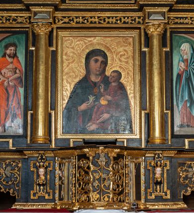 Zdjęcie nr 2: Ołtarz przyścienny, architektoniczny, trójosiowy, dwukondygnacjowy. Nastawa ołtarzowa ustawiona na prostopadłościennym stole ołtarzowym, zasłanym czerwonym materiałem. Predella na niskim cokoliku w formie półwałku, zamknięta u góry puklowanym gzymsem. W osi środkowej wmontowane tabernakulum ozdobione bujną, płaskorzeźbioną winną latoroślą. Po jego bokach ścianki z lustrami, flankowane parą spiralnie skręconych laskowań. W osiach bocznych predelli płyciny o uszatych narożach, w polu których znajdują się pilastry hermowe ze skierowanymi na wprost kobiecymi głowami. Na skrajach predelli konsolki, bogato dekorowane wicią, zawijającą się w wolutki, zdobioną perełkowaniem; na brzegu konsolki skierowana ku dołowi głowa. Pierwsza kondygnacja artykułowana parą kolumn o korynckich kapitelach, wspierających niepełne belkowanie, wyłamane na ich osi. W polu głównym obraz Matki Boskiej z Dzieciątkiem, w osiach bocznych wmontowane skrzydła tryptyku z przedstawieniami: Ecce Homo po lewej stronie oraz Matki Boskiej Bolesnej po prawej stronie. Każda z osi ujęta na brzegach obramowaniem w kształcie stojącego prostokąta o uszatych narożnikach. Fryz dekorowany symetryczną wicią roślinną, nad kolumnami srebrzone rauty. Druga kondygnacja mniejsza, flankowana analogicznymi kolumnami, wspierającymi podobne belkowanie. W polu głównym obraz św. Andrzeja w kształcie stojącego prostokąta. W lewej osi bocznej obraz św. Wojciecha, a w prawej św. Stanisława, oba zamknięte łukiem nadwieszonym. Po bokach kondygnacji uszy o wykroju okuciowym, zdobione wicią oraz podwieszonymi girlandami z owocami winogron. Nad ołtarzem zamocowana promienista gloria, w polu której znajduje się oko Opatrzności otoczone wieńcem z obłoków oraz sześcioma skrzydlatymi główkami anielskimi. Struktura malowana na kolor czarny, kolumny i ornamentyka złocone, detale srebrzone.
