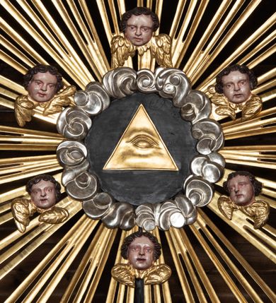 Zdjęcie nr 21: Ołtarz przyścienny, architektoniczny, trójosiowy, dwukondygnacjowy. Nastawa ołtarzowa ustawiona na prostopadłościennym stole ołtarzowym, zasłanym czerwonym materiałem. Predella na niskim cokoliku w formie półwałku, zamknięta u góry puklowanym gzymsem. W osi środkowej wmontowane tabernakulum ozdobione bujną, płaskorzeźbioną winną latoroślą. Po jego bokach ścianki z lustrami, flankowane parą spiralnie skręconych laskowań. W osiach bocznych predelli płyciny o uszatych narożach, w polu których znajdują się pilastry hermowe ze skierowanymi na wprost kobiecymi głowami. Na skrajach predelli konsolki, bogato dekorowane wicią, zawijającą się w wolutki, zdobioną perełkowaniem; na brzegu konsolki skierowana ku dołowi głowa. Pierwsza kondygnacja artykułowana parą kolumn o korynckich kapitelach, wspierających niepełne belkowanie, wyłamane na ich osi. W polu głównym obraz Matki Boskiej z Dzieciątkiem, w osiach bocznych wmontowane skrzydła tryptyku z przedstawieniami: Ecce Homo po lewej stronie oraz Matki Boskiej Bolesnej po prawej stronie. Każda z osi ujęta na brzegach obramowaniem w kształcie stojącego prostokąta o uszatych narożnikach. Fryz dekorowany symetryczną wicią roślinną, nad kolumnami srebrzone rauty. Druga kondygnacja mniejsza, flankowana analogicznymi kolumnami, wspierającymi podobne belkowanie. W polu głównym obraz św. Andrzeja w kształcie stojącego prostokąta. W lewej osi bocznej obraz św. Wojciecha, a w prawej św. Stanisława, oba zamknięte łukiem nadwieszonym. Po bokach kondygnacji uszy o wykroju okuciowym, zdobione wicią oraz podwieszonymi girlandami z owocami winogron. Nad ołtarzem zamocowana promienista gloria, w polu której znajduje się oko Opatrzności otoczone wieńcem z obłoków oraz sześcioma skrzydlatymi główkami anielskimi. Struktura malowana na kolor czarny, kolumny i ornamentyka złocone, detale srebrzone.