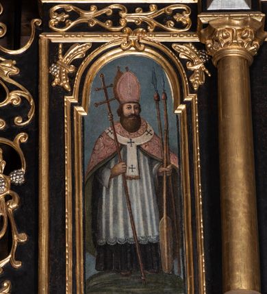 Zdjęcie nr 9: Ołtarz przyścienny, architektoniczny, trójosiowy, dwukondygnacjowy. Nastawa ołtarzowa ustawiona na prostopadłościennym stole ołtarzowym, zasłanym czerwonym materiałem. Predella na niskim cokoliku w formie półwałku, zamknięta u góry puklowanym gzymsem. W osi środkowej wmontowane tabernakulum ozdobione bujną, płaskorzeźbioną winną latoroślą. Po jego bokach ścianki z lustrami, flankowane parą spiralnie skręconych laskowań. W osiach bocznych predelli płyciny o uszatych narożach, w polu których znajdują się pilastry hermowe ze skierowanymi na wprost kobiecymi głowami. Na skrajach predelli konsolki, bogato dekorowane wicią, zawijającą się w wolutki, zdobioną perełkowaniem; na brzegu konsolki skierowana ku dołowi głowa. Pierwsza kondygnacja artykułowana parą kolumn o korynckich kapitelach, wspierających niepełne belkowanie, wyłamane na ich osi. W polu głównym obraz Matki Boskiej z Dzieciątkiem, w osiach bocznych wmontowane skrzydła tryptyku z przedstawieniami: Ecce Homo po lewej stronie oraz Matki Boskiej Bolesnej po prawej stronie. Każda z osi ujęta na brzegach obramowaniem w kształcie stojącego prostokąta o uszatych narożnikach. Fryz dekorowany symetryczną wicią roślinną, nad kolumnami srebrzone rauty. Druga kondygnacja mniejsza, flankowana analogicznymi kolumnami, wspierającymi podobne belkowanie. W polu głównym obraz św. Andrzeja w kształcie stojącego prostokąta. W lewej osi bocznej obraz św. Wojciecha, a w prawej św. Stanisława, oba zamknięte łukiem nadwieszonym. Po bokach kondygnacji uszy o wykroju okuciowym, zdobione wicią oraz podwieszonymi girlandami z owocami winogron. Nad ołtarzem zamocowana promienista gloria, w polu której znajduje się oko Opatrzności otoczone wieńcem z obłoków oraz sześcioma skrzydlatymi główkami anielskimi. Struktura malowana na kolor czarny, kolumny i ornamentyka złocone, detale srebrzone.