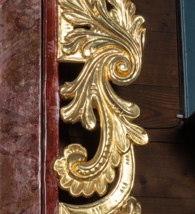 Zdjęcie nr 5: Ołtarz przyścienny, architektoniczny, jednokondygnacyjny, jednoosiowy ze zwieńczeniem. Mensa prostopadłościenna, drewniana, ustawiona na cokole, zamknięta profilowanym gzymsem. Antepedium zdobione malowaną płyciną w kształcie leżącego prostokąta o wklęsłych narożach i zryzalitowanym górnym i dolnym boku. W polu baranek apokaliptyczny na księdze zamkniętej siedmioma pieczęciami, po bokach girlandy kwiatowe, tło ciemnozielone. Nastawa ołtarzowa ustawiona na niskim cokole o wysuniętych do przodu impostach, na których ustawiona jest para kolumn, wspierających przerwane belkowanie i wolutowy przyczółek. Pośrodku w ramie ozdobionej płaskorzeźbionymi liśćmi obraz Trójcy Świętej w kształcie stojącego prostokąta, zamkniętego łukiem wklęsło-wypukłym z uskokami. Po bokach obrazu zwisy z camapnul. Fryz dekorowany rozetkami i liśćmi akantu. Za kolumnami prostokątne płyciny, marmoryzowane. W zwieńczeniu płaskorzeźba św. Tekli z krzyżem i płonącym stosem na tle obłoków i promienistej glorii z czterema uskrzydlonymi główkami anielskimi. Po bokach ołtarza akantowe uszy, przeplecione karbowaną wstęgą. Imposty w partii cokołu zdobione płycinami w kształcie niewielkich prostokątów, wypełnione liśćmi akantu. Struktura marmoryzowana na kolor ciemnoniebieski, trzony kolumn marmoryzowane na kolor zielono-beżowy, profilowania na kolor bordowy, detale i ornamentyka złocone. 