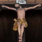 Zdjęcie nr 1: Krucyfiks z rzeźbą Chrystusa w typie Christo morte. Ciało zawieszone na niemal wyprostowanych ramionach; głowa silnie przechylona na prawe ramię; nogi delikatnie ugięte w kolanach, stopy przebite jednym gwoździem w układzie prawa na lewą. Twarz podłużna z zamkniętymi oczami i długim nosem, okolona krótkim zarostem. Na głowie zielona korona cierniowa. Włosy długie, czarne, opadające na prawe ramię oraz na plecy, silnie zawinięte do tyłu w drobne pukle. Klatka piersiowa szeroka z delikatnie, łukowato zaznaczoną linią żeber i mostka. Perizonium przewiązane na prawym boku w supeł z prawym końcem zwisającym wzdłuż prawego uda. Nad głową Chrystusa znajduje się biały titulus z napisem „INRI” w polu. Polichromia naturalistyczna w odsłoniętych partiach ciała z zaznaczonymi śladami męki, perizonium złocone. Krzyż o szerokich ramionach, prosty, malowany na czarno. 