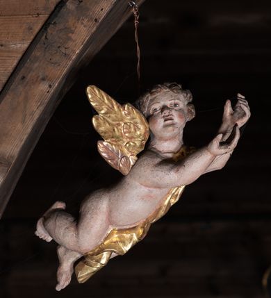 Zdjęcie nr 6: Krucyfiks z rzeźbą Chrystusa w typie Christo morte. Ciało zawieszone na niemal wyprostowanych ramionach; głowa silnie przechylona na prawe ramię; nogi delikatnie ugięte w kolanach, stopy przebite jednym gwoździem w układzie prawa na lewą. Twarz podłużna z zamkniętymi oczami i długim nosem, okolona krótkim zarostem. Na głowie zielona korona cierniowa. Włosy długie, czarne, opadające na prawe ramię oraz na plecy, silnie zawinięte do tyłu w drobne pukle. Klatka piersiowa szeroka z delikatnie, łukowato zaznaczoną linią żeber i mostka. Perizonium przewiązane na prawym boku w supeł z prawym końcem zwisającym wzdłuż prawego uda. Nad głową Chrystusa znajduje się biały titulus z napisem „INRI” w polu. Polichromia naturalistyczna w odsłoniętych partiach ciała z zaznaczonymi śladami męki, perizonium złocone. Krzyż o szerokich ramionach, prosty, malowany na czarno. 