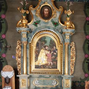 Zdjęcie nr 1: Nastawa ołtarzowa drewniana, architektoniczna, jednoosiowa, jednokondygnacyjna ze zwieńczeniem. Mensa w typie sarkofagowym, wklęsło-wypukła, zwężający się ku dołowi, zamknięta gzymsem; naroża ujęte fragmentami rocaille'u, na froncie rocaille’owy kartusz; portatyl kamienny. Retabulum posadowione na cokole zryzalitowanym po bokach, zamkniętym silnie wysuniętym gzymsem; ujęte parą kolumn o kapitelach korynckich dźwigających imposty, których fryz przebiega przez całą szerokość retabulum, przyjmując nad polem środkowym formę łuku półkolistego nadwieszonego. W polu środkowym znajduje się nisza w formie kwadratu zamkniętego łukiem półkolistym nadwieszonym z płaskorzeźbioną sceną Świętej Rodziny w warsztacie, ujętego trzema ramami. Zwieńczenie ma formę zbliżoną do trapezu. Jest flankowane spływami wolutowymi i zamknięte baldachimem z profilowanym cokołem. W polu medalion otoczony profilowaną ramą z obrazem „Veraikon”. Cokoły kolumn dekorowane z trzech stron płycinami z ornamentem roślinnym; w polu predelli płycina w formie leżącego prostokąta o wypukłych ściankach bocznych z ornamentem roślinnym. Kondygnacja ujęta uszami utworzonymi z mięsistego akantu. Na fryzie rozety; na impostach rokokowe wazony z dużymi kwiatami słonecznika, róż i lilii, rama obrazu zwieńczenia dekorowana ornamentem roślinnym; u spodu akant z rozetami. Baldachim z podwieszonym lambrekinem; na jego cokole rokokowy wazon z dużymi kwiatami słonecznika, róż i lilii. Struktura marmoryzowana w kolorze szaro-niebieskim; ornamentyka, profile i kolumny złocone i srebrzone.