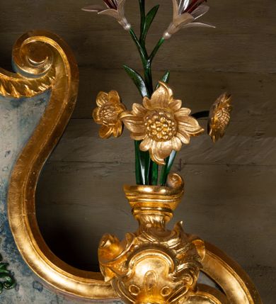 Zdjęcie nr 9: Nastawa ołtarzowa drewniana, architektoniczna, jednoosiowa, jednokondygnacyjna ze zwieńczeniem. Mensa w typie sarkofagowym, wklęsło-wypukła, zwężający się ku dołowi, zamknięta gzymsem; naroża ujęte fragmentami rocaille'u, na froncie rocaille’owy kartusz; portatyl kamienny. Retabulum posadowione na cokole zryzalitowanym po bokach, zamkniętym silnie wysuniętym gzymsem; ujęte parą kolumn o kapitelach korynckich dźwigających imposty, których fryz przebiega przez całą szerokość retabulum, przyjmując nad polem środkowym formę łuku półkolistego nadwieszonego. W polu środkowym znajduje się nisza w formie kwadratu zamkniętego łukiem półkolistym nadwieszonym z płaskorzeźbioną sceną Świętej Rodziny w warsztacie, ujętego trzema ramami. Zwieńczenie ma formę zbliżoną do trapezu. Jest flankowane spływami wolutowymi i zamknięte baldachimem z profilowanym cokołem. W polu medalion otoczony profilowaną ramą z obrazem „Veraikon”. Cokoły kolumn dekorowane z trzech stron płycinami z ornamentem roślinnym; w polu predelli płycina w formie leżącego prostokąta o wypukłych ściankach bocznych z ornamentem roślinnym. Kondygnacja ujęta uszami utworzonymi z mięsistego akantu. Na fryzie rozety; na impostach rokokowe wazony z dużymi kwiatami słonecznika, róż i lilii, rama obrazu zwieńczenia dekorowana ornamentem roślinnym; u spodu akant z rozetami. Baldachim z podwieszonym lambrekinem; na jego cokole rokokowy wazon z dużymi kwiatami słonecznika, róż i lilii. Struktura marmoryzowana w kolorze szaro-niebieskim; ornamentyka, profile i kolumny złocone i srebrzone.