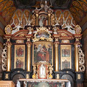 Zdjęcie nr 1: Ołtarz trójosiowy, dwukondygnacyjny z bramkami o formach architektonicznych, uszaty. Mensa murowana, prostopadłościenna z drewnianym antepedium ujętym profilowaną ramą z malowaną dekoracją roślinną. W polu malowane na płótnie przedstawienie adoracji Najświętszego Sakramentu. Tabernakulum w formie prostopadłościanu, o wypukłej ściance frontowej, ujętej pilastrami o kapitelach w formie akantowych konsol podtrzymujących pełne belkowanie. Na trzonach owalne lustra w akantowych ramach. W zwieńczeniu dwie uskrzydlone główki anielskie. Na metalowych drzwiczkach krucyfiks oraz kielich z hostią w otoczeniu winnych gron i kłosów (na odwrociu). Naroża tabernakulum flankuje para aniołów ustawionych na wolutowych konsolach. Nastawa umieszczona na wysokim cokole z bramkami mieszczącymi obrazy Chrystusa w typie Ecce Homo (z lewej) oraz Matki Boskiej Bolesnej (z prawej). Cokół artykułowany wysokimi postumentami, na których ustawione są kolumny. W polach postumentów złocona dekoracja akantowa. Kondygnacja pierwsza trójosiowa, artykułowana złoconymi kolumnami o korynckich kapitelach, ujęta srebrzonymi akantowymi uszami (suchy akant). Kolumny dźwigają pełne belkowanie, wyłamane na osiach podpór oraz odcinki przyczółka, na których siedzą figury aniołów w białych szatach. Dodatkowo, w osiach kolumn umieszczone mniejsze figury klęczących aniołów (osie wewnętrzne) oraz marmoryzowane, owalne kartusze ujęte złoconymi ramami z ornamentem małżowinowo-chrząstkowym (osie zewnętrzne). W partii fryzu złocone rozetki oraz marmoryzowane, owalne kartusze ujęte złoconym akantem. Gzyms profilowany, dekorowany dodatkowo złoconym kimationem. W polu środkowym prostokątny obraz przedstawiający Rodzinę Marii. Na zasuwie umieszczony obraz z wizerunkiem św. Katarzyny Aleksandryjskiej. Powyżej, w osi ołtarza obraz ze sceną Koronacji Marii, o nieregularnym kształcie w akantowej ramie, zwieńczonej koroną. W osiach bocznych umieszczone skrzydła boczne dawnego, gotyckiego tryptyku z wizerunkami św. Jana Chrzciciela i św. Barbary (z lewej) oraz św. Stanisława biskupa i św. Katarzyny Aleksandryjskiej (z prawej). Zwieńczenie ołtarza w formie edikuli ujętej złoconymi, korynckimi kolumnami oraz złoconymi, akantowymi uszami. Po bokach niewielkie figury klęczących aniołów. Podpory dźwigają wyłamane belkowanie dekorowane kimationem i rozetkami, łukowato wyginające się w osi ołtarza. W polu obraz w kształcie stojącego prostokąta zamkniętego łukiem półkolistym ze sceną Zwiastowania. Całość zwieńczona srebrzonym baldachimem z podwieszonej tkaniny przewiązanej złotym sznurem ze złoconą koroną umieszczoną na szczycie. Struktura ołtarza marmoryzowana w odcieniu ciemnoszarym, profile i płyciny na filarach marmoryzowane w kolorze bordowym, ornamentyka złocona i posrebrzana.