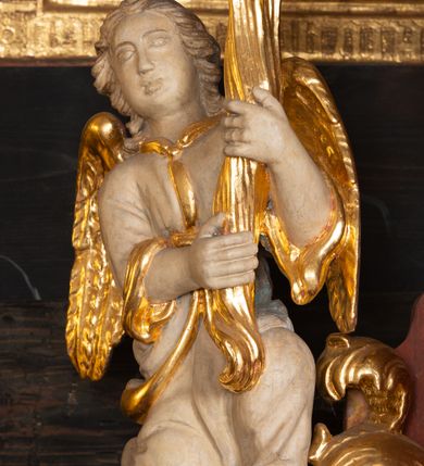 Zdjęcie nr 8: Ołtarz trójosiowy, dwukondygnacyjny z bramkami o formach architektonicznych, uszaty. Mensa murowana, prostopadłościenna z drewnianym antepedium ujętym profilowaną ramą z malowaną dekoracją roślinną. W polu malowane na płótnie przedstawienie adoracji Najświętszego Sakramentu. Tabernakulum w formie prostopadłościanu, o wypukłej ściance frontowej, ujętej pilastrami o kapitelach w formie akantowych konsol podtrzymujących pełne belkowanie. Na trzonach owalne lustra w akantowych ramach. W zwieńczeniu dwie uskrzydlone główki anielskie. Na metalowych drzwiczkach krucyfiks oraz kielich z hostią w otoczeniu winnych gron i kłosów (na odwrociu). Naroża tabernakulum flankuje para aniołów ustawionych na wolutowych konsolach. Nastawa umieszczona na wysokim cokole z bramkami mieszczącymi obrazy Chrystusa w typie Ecce Homo (z lewej) oraz Matki Boskiej Bolesnej (z prawej). Cokół artykułowany wysokimi postumentami, na których ustawione są kolumny. W polach postumentów złocona dekoracja akantowa. Kondygnacja pierwsza trójosiowa, artykułowana złoconymi kolumnami o korynckich kapitelach, ujęta srebrzonymi akantowymi uszami (suchy akant). Kolumny dźwigają pełne belkowanie, wyłamane na osiach podpór oraz odcinki przyczółka, na których siedzą figury aniołów w białych szatach. Dodatkowo, w osiach kolumn umieszczone mniejsze figury klęczących aniołów (osie wewnętrzne) oraz marmoryzowane, owalne kartusze ujęte złoconymi ramami z ornamentem małżowinowo-chrząstkowym (osie zewnętrzne). W partii fryzu złocone rozetki oraz marmoryzowane, owalne kartusze ujęte złoconym akantem. Gzyms profilowany, dekorowany dodatkowo złoconym kimationem. W polu środkowym prostokątny obraz przedstawiający Rodzinę Marii. Na zasuwie umieszczony obraz z wizerunkiem św. Katarzyny Aleksandryjskiej. Powyżej, w osi ołtarza obraz ze sceną Koronacji Marii, o nieregularnym kształcie w akantowej ramie, zwieńczonej koroną. W osiach bocznych umieszczone skrzydła boczne dawnego, gotyckiego tryptyku z wizerunkami św. Jana Chrzciciela i św. Barbary (z lewej) oraz św. Stanisława biskupa i św. Katarzyny Aleksandryjskiej (z prawej). Zwieńczenie ołtarza w formie edikuli ujętej złoconymi, korynckimi kolumnami oraz złoconymi, akantowymi uszami. Po bokach niewielkie figury klęczących aniołów. Podpory dźwigają wyłamane belkowanie dekorowane kimationem i rozetkami, łukowato wyginające się w osi ołtarza. W polu obraz w kształcie stojącego prostokąta zamkniętego łukiem półkolistym ze sceną Zwiastowania. Całość zwieńczona srebrzonym baldachimem z podwieszonej tkaniny przewiązanej złotym sznurem ze złoconą koroną umieszczoną na szczycie. Struktura ołtarza marmoryzowana w odcieniu ciemnoszarym, profile i płyciny na filarach marmoryzowane w kolorze bordowym, ornamentyka złocona i posrebrzana.