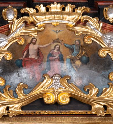 Zdjęcie nr 23: Ołtarz trójosiowy, dwukondygnacyjny z bramkami o formach architektonicznych, uszaty. Mensa murowana, prostopadłościenna z drewnianym antepedium ujętym profilowaną ramą z malowaną dekoracją roślinną. W polu malowane na płótnie przedstawienie adoracji Najświętszego Sakramentu. Tabernakulum w formie prostopadłościanu, o wypukłej ściance frontowej, ujętej pilastrami o kapitelach w formie akantowych konsol podtrzymujących pełne belkowanie. Na trzonach owalne lustra w akantowych ramach. W zwieńczeniu dwie uskrzydlone główki anielskie. Na metalowych drzwiczkach krucyfiks oraz kielich z hostią w otoczeniu winnych gron i kłosów (na odwrociu). Naroża tabernakulum flankuje para aniołów ustawionych na wolutowych konsolach. Nastawa umieszczona na wysokim cokole z bramkami mieszczącymi obrazy Chrystusa w typie Ecce Homo (z lewej) oraz Matki Boskiej Bolesnej (z prawej). Cokół artykułowany wysokimi postumentami, na których ustawione są kolumny. W polach postumentów złocona dekoracja akantowa. Kondygnacja pierwsza trójosiowa, artykułowana złoconymi kolumnami o korynckich kapitelach, ujęta srebrzonymi akantowymi uszami (suchy akant). Kolumny dźwigają pełne belkowanie, wyłamane na osiach podpór oraz odcinki przyczółka, na których siedzą figury aniołów w białych szatach. Dodatkowo, w osiach kolumn umieszczone mniejsze figury klęczących aniołów (osie wewnętrzne) oraz marmoryzowane, owalne kartusze ujęte złoconymi ramami z ornamentem małżowinowo-chrząstkowym (osie zewnętrzne). W partii fryzu złocone rozetki oraz marmoryzowane, owalne kartusze ujęte złoconym akantem. Gzyms profilowany, dekorowany dodatkowo złoconym kimationem. W polu środkowym prostokątny obraz przedstawiający Rodzinę Marii. Na zasuwie umieszczony obraz z wizerunkiem św. Katarzyny Aleksandryjskiej. Powyżej, w osi ołtarza obraz ze sceną Koronacji Marii, o nieregularnym kształcie w akantowej ramie, zwieńczonej koroną. W osiach bocznych umieszczone skrzydła boczne dawnego, gotyckiego tryptyku z wizerunkami św. Jana Chrzciciela i św. Barbary (z lewej) oraz św. Stanisława biskupa i św. Katarzyny Aleksandryjskiej (z prawej). Zwieńczenie ołtarza w formie edikuli ujętej złoconymi, korynckimi kolumnami oraz złoconymi, akantowymi uszami. Po bokach niewielkie figury klęczących aniołów. Podpory dźwigają wyłamane belkowanie dekorowane kimationem i rozetkami, łukowato wyginające się w osi ołtarza. W polu obraz w kształcie stojącego prostokąta zamkniętego łukiem półkolistym ze sceną Zwiastowania. Całość zwieńczona srebrzonym baldachimem z podwieszonej tkaniny przewiązanej złotym sznurem ze złoconą koroną umieszczoną na szczycie. Struktura ołtarza marmoryzowana w odcieniu ciemnoszarym, profile i płyciny na filarach marmoryzowane w kolorze bordowym, ornamentyka złocona i posrebrzana.