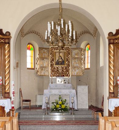 Zdjęcie nr 5: Nastawa ołtarzowa przyścienna, architektoniczna, jednokondygnacyjna ze zwieńczeniem. Mensa skrzyniowa, prostopadłościenna, ustawiona na jednym stopniu. Antepedium trójpolowe, obramione profilowanymi listwami, w narożach ujęte skręconymi, złoconymi kolumnami. W środkowym polu hierogram IHS, w bocznych motywy kwiatu dziewięćsiłu. Portatyl w formie kamiennej płytki. Tabernakulum w kształcie niewielkiej prostopadłościennej szafki, ujęte w narożach skręconymi kolumnami o kapitelach kostkowych, podtrzymujących profilowany gzyms. Od frontu drzwiczki w formie prostokąta zamkniętego łukiem odcinkowym, z rytą dekoracją roślinną i aplikowanym złoconym kielichem. Nastawa płaska, flankowana skręconymi, złoconymi kolumnami, ustawionymi na cokołach, dekorowanych rozetką. Kolumny zwieńczone kostkowymi kapitelami z rozetkami, nad którymi przerwany przyczółek. Nad polem środkowym zredukowane belkowanie, z fryzem zdobionym ukośną kratką. Zwieńczenie ujęte dwoma wolutami z uskokiem, dekorowanymi na krańcach rozetkami pomiędzy którymi półokrągłe wycięcie i łaciński krzyż. W polu głównym obraz św. Józefa z Dzieciątkiem w prostokątnej ramie, dookoła obwiedziony szerokim profilowaniem. Struktura bejcowana, pokryta lakierem, detale i kolumny złocone. 
