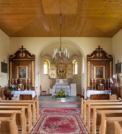 Zdjęcie nr 7: Nastawa ołtarzowa przyścienna, architektoniczna, jednokondygnacyjna ze zwieńczeniem. Mensa skrzyniowa, prostopadłościenna, ustawiona na jednym stopniu. Antepedium trójpolowe, obramione profilowanymi listwami, w narożach ujęte skręconymi, złoconymi kolumnami. W środkowym polu hierogram IHS, w bocznych motywy kwiatu dziewięćsiłu. Portatyl w formie kamiennej płytki. Tabernakulum w kształcie niewielkiej prostopadłościennej szafki, ujęte w narożach skręconymi kolumnami o kapitelach kostkowych, podtrzymujących profilowany gzyms. Od frontu drzwiczki w formie prostokąta zamkniętego łukiem odcinkowym, z rytą dekoracją roślinną i aplikowanym złoconym kielichem. Nastawa płaska, flankowana skręconymi, złoconymi kolumnami, ustawionymi na cokołach, dekorowanych rozetką. Kolumny zwieńczone kostkowymi kapitelami z rozetkami, nad którymi przerwany przyczółek. Nad polem środkowym zredukowane belkowanie, z fryzem zdobionym ukośną kratką. Zwieńczenie ujęte dwoma wolutami z uskokiem, dekorowanymi na krańcach rozetkami pomiędzy którymi półokrągłe wycięcie i łaciński krzyż. W polu głównym obraz św. Józefa z Dzieciątkiem w prostokątnej ramie, dookoła obwiedziony szerokim profilowaniem. Struktura bejcowana, pokryta lakierem, detale i kolumny złocone. 
