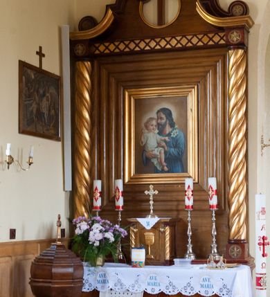 Zdjęcie nr 2: Nastawa ołtarzowa przyścienna, architektoniczna, jednokondygnacyjna ze zwieńczeniem. Mensa skrzyniowa, prostopadłościenna, ustawiona na jednym stopniu. Antepedium trójpolowe, obramione profilowanymi listwami, w narożach ujęte skręconymi, złoconymi kolumnami. W środkowym polu hierogram IHS, w bocznych motywy kwiatu dziewięćsiłu. Portatyl w formie kamiennej płytki. Tabernakulum w kształcie niewielkiej prostopadłościennej szafki, ujęte w narożach skręconymi kolumnami o kapitelach kostkowych, podtrzymujących profilowany gzyms. Od frontu drzwiczki w formie prostokąta zamkniętego łukiem odcinkowym, z rytą dekoracją roślinną i aplikowanym złoconym kielichem. Nastawa płaska, flankowana skręconymi, złoconymi kolumnami, ustawionymi na cokołach, dekorowanych rozetką. Kolumny zwieńczone kostkowymi kapitelami z rozetkami, nad którymi przerwany przyczółek. Nad polem środkowym zredukowane belkowanie, z fryzem zdobionym ukośną kratką. Zwieńczenie ujęte dwoma wolutami z uskokiem, dekorowanymi na krańcach rozetkami pomiędzy którymi półokrągłe wycięcie i łaciński krzyż. W polu głównym obraz św. Józefa z Dzieciątkiem w prostokątnej ramie, dookoła obwiedziony szerokim profilowaniem. Struktura bejcowana, pokryta lakierem, detale i kolumny złocone. 
