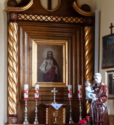 Zdjęcie nr 3: Nastawa ołtarzowa przyścienna, architektoniczna, jednokondygnacyjna ze zwieńczeniem. Mensa skrzyniowa, prostopadłościenna, ustawiona na jednym stopniu. Antepedium trójpolowe, obramione profilowanymi listwami, w narożach ujęte skręconymi, złoconymi kolumnami. W środkowym polu hierogram IHS, w bocznych motywy kwiatu dziewięćsiłu. Portatyl w formie kamiennej płytki. Tabernakulum w kształcie niewielkiej prostopadłościennej szafki, ujęte w narożach skręconymi kolumnami o kapitelach kostkowych, podtrzymujących profilowany gzyms. Od frontu drzwiczki w formie prostokąta zamkniętego łukiem odcinkowym, z rytą dekoracją roślinną i aplikowanym złoconym kielichem. Nastawa płaska, flankowana skręconymi, złoconymi kolumnami, ustawionymi na cokołach, dekorowanych rozetką. Kolumny zwieńczone kostkowymi kapitelami, ozdobionymi rozetką, nad którymi przerwany przyczółek. Nad polem środkowym zredukowane belkowanie, z fryzem zdobionym ukośną kratką. Zwieńczenie ujęte dwoma wolutami z uskokiem, dekorowanymi na krańcach rozetkami, pomiędzy którymi półokrągłe wycięcie i łaciński krzyż. W polu głównym obraz „Najświętsze Serce Jezusa” w prostokątnej ramie, dookoła obwiedziony szerokim profilowaniem. Struktura bejcowana, pokryta lakierem, detale i kolumny złocone. 
