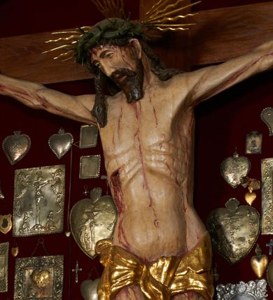 Zdjęcie nr 1: Krzyż drewniany o prostych ramionach z figurą w typie Cristo vivo przybitą trzema gwoździami. Sylwetka w lekkim zwisie, o szerokim rozłożeniu ramion, z głową przechyloną na prawe ramię; nogi ugięte w kolanach, skierowane w prawą stronę, stopy w układzie prawa na lewą. Twarz pociągła o wąskich, otwartych oczach, dużym nosie, otwartych ustach, okolona brodą oraz włosami skręconymi w rurkowate pukle. Na głowie korona cierniowa, wokół niej trzy wiązki promieni. Ciało wychudzone, o zaznaczonych mięśniach ramion i nóg oraz sumarycznie kształtowanej klatce piersiowej z podkreślonymi liniami żeber i wypukłością brzucha oraz ze śladami męki w postaci rzeźbionych kropel krwi wypływającej z ran. Perizonium krótkie, ściśle opinające biodra, zawiązane w partii podbrzusza, ze zwisem na prawym biodrze. Na górnym zakończeniu pionowej belki krzyża banderola z napisem „INRI”. Ciało polichromowane naturalistycznie, perizonium pozłacane. 
