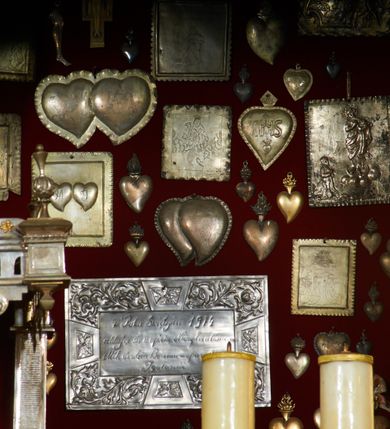 Zdjęcie nr 14: Krzyż drewniany o prostych ramionach z figurą w typie Cristo vivo przybitą trzema gwoździami. Sylwetka w lekkim zwisie, o szerokim rozłożeniu ramion, z głową przechyloną na prawe ramię; nogi ugięte w kolanach, skierowane w prawą stronę, stopy w układzie prawa na lewą. Twarz pociągła o wąskich, otwartych oczach, dużym nosie, otwartych ustach, okolona brodą oraz włosami skręconymi w rurkowate pukle. Na głowie korona cierniowa, wokół niej trzy wiązki promieni. Ciało wychudzone, o zaznaczonych mięśniach ramion i nóg oraz sumarycznie kształtowanej klatce piersiowej z podkreślonymi liniami żeber i wypukłością brzucha oraz ze śladami męki w postaci rzeźbionych kropel krwi wypływającej z ran. Perizonium krótkie, ściśle opinające biodra, zawiązane w partii podbrzusza, ze zwisem na prawym biodrze. Na górnym zakończeniu pionowej belki krzyża banderola z napisem „INRI”. Ciało polichromowane naturalistycznie, perizonium pozłacane. 
