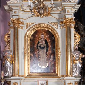 Zdjęcie nr 1: Nastawa ołtarzowa architektoniczna, jednoosiowa, jednokondygnacyjna ze zwieńczeniem, ustawiona na dwustrefowym cokole, z wyodrębnionymi po bokach dwoma prostopadłościennymi postumentami. Ołtarz drewniany, prostopadłościenny. Antepedium w formie poziomego prostokąta w profilowanej ramie, jego powierzchnia podzielona jest wstęgami na trzy owalne pola, wewnątrz każdego wazon z bukietem kwiatów z owocami, dookoła nich w niewielkich polach przedstawienia orłów. Na mensie ustawione tabernakulum w formie prostopadłościennej skrzynki z drzwiczkami w formie pionowego prostokąta, z przedstawieniem hostii w glorii promienistej.
Środkowa część struktury nastawy ujęta parą kolumn kompozytowych na tle zwielokrotnionych pilastrów, ustawionych na wyodrębnionych cokołach dekorowanych rocaille'm. Kolumny dźwigają pełne belkowanie wyłamane na ich osi oraz odcinki przerwanego, falistego przyczółka, na którym siedzą putta. W polu środkowym obraz z przedstawieniem Matki Boskiej Niepokalanie Poczętej ze św. Heleną i św. Wojciechem w formie pionowego prostokąta zamkniętego łukiem półkolistym, w profilowanej ramie dekorowanej rocaille'm. Nad obrazem, w partii belkowania rocaille'owy kartusz z napisem „TOTA / PULCHRA EST MARIA / ET MACULA ORDINATIS/ IN TE”. Po zewnętrznej stronie kolumn na wspornikach stoją figury św. Anny i św. Joachima. Ołtarz flankowany uszami utworzonymi z motywów rocaille. Zwieńczenie w formie trapezu ujętego spływami wolutowymi, zamkniętego łukiem półkolistym nadwieszonym, obwiedzionego profilowanymi listwami, zwieńczonego gzymsem, dekorowanym rocaiile'owym kartuszem i ornamentem roślinnym. W polu powtarzającym kształt zwieńczenia obraz Narodzenia Marii w profilowanej ramie. Struktura ołtarza polichromowana w kolorze bieli, ornamentyka, profile i kolumny pozłacane.





