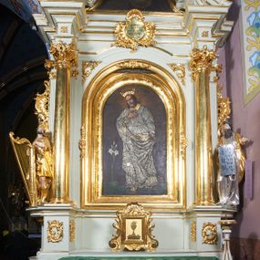 Zdjęcie nr 1: Nastawa ołtarzowa architektoniczna, jednoosiowa, jednokondygnacyjna ze zwieńczeniem, ustawiona na dwustrefowym cokole, z wyodrębnionymi po bokach dwoma prostopadłościennymi postumentami. Ołtarz drewniany, prostopadłościenny. Antepedium w formie poziomego prostokąta w profilowanej ramie, w polu podzielone jest wstęgami na trzy owalne pola, wewnątrz każdego korona w wieńcu z ornamentu roślinnego, dookoła w niewielkich polach ptaki z gałązkami w dziobach. Na mensie ustawione tabernakulum w formie prostopadłościennej skrzynki, ujętej spływami wolutowymi, zwieńczonej motywem rocaille. Drzwiczki w formie pionowego prostokąta, w profilowanej ramie z rytym przedstawieniem kielicha z hostią na obłoku. 
Środkowa część struktury nastawy ujęta parą kolumn kompozytowych ustawionych na tle zwielokrotnionych pilastrów oraz na wyodrębnionych cokołach dekorowanych rocaille&#039;m. Kolumny dźwigają pełne belkowanie wyłamane na ich osi oraz odcinki przerwanego, falistego przyczółka z siedzącymi na nich puttami. W polu środkowym obraz z przedstawieniem św. Józefa w formie pionowego prostokąta zamkniętego łukiem półkolistym, w profilowanej ramie dekorowanej rocaille&#039;m. Nad obrazem, w partii belkowania rocaille&#039;owy kartusz z napisem „SANCTE / JOSEPH / INTERCEDE / PRO NOBIS”. Po zewnętrznej stronie kolumn na wspornikach stoją figury Dawida i Mojżesza. Ołtarz flankowany uszami utworzonymi z motywów rocaille. Zwieńczenie w formie trapezu ujętego spływami wolutowymi, zamkniętego łukiem półkolistym nadwieszonym, obwiedzionego profilowanymi listwami, zwieńczonego gzymsem, dekorowanym kartuszem z motywów rocaille. W polu powtarzającym kształt zwieńczenia obraz św. Kryspina z Viterbo w profilowanej ramie. Struktura ołtarza polichromowana w kolorze bieli, ornamentyka, profile i kolumny pozłacane.

