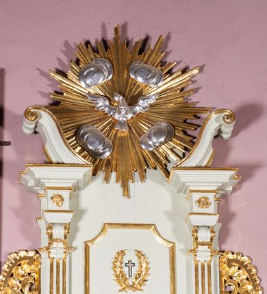 Zdjęcie nr 8: Ambona wisząca, przyścienna, z dostępem od strony północnej w formie podestu z balustradą, prowadzącego do drzwi przekutych w murze. Kosz na planie zbliżonym do kwadratu, o wklęsło-wypukłych ściankach, na cokole dekorowanym rocaille'em, z podwieszeniem w formie stożka ujętego spływami wolutowymi i zakończonego szyszką. Ścianki kosza ujęte w narożach pilastrami o trzonach w formie spływów wolutowych dekorowanych kampanulami, podtrzymujących belkowanie z gzymsem tworzącym parapet. Na ściankach płyciny zdobione rocaille'em. Balustrada podestu pełna, dekorowana płycinami ze stylizowanym ornamentem roślinnym. Zaplecek flankowany pilastrami o kanelowanych trzonach, o kapitelach w formie konsol dźwigających imposty oraz fragmenty przerwanego, wolutowego, odwróconego na zewnątrz przyczółka. W polu zaplecka płycina w kształcie stojącego prostokąta o wklęsłych narożach, z malowanym krzyżem ujętym wieńcem laurowym i tablicami Dekalogu. Zaplecek flankowany uszami w formie stylizowanego rocaille'u. Całość zwieńczona rzeźbą gołębicy Ducha Świętego w glorii promienistej. Struktura ambony polichromowana na kolor biały, profile i ornamentyka złocone, detale srebrzone. 