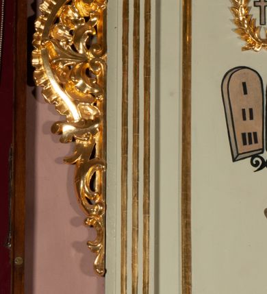 Zdjęcie nr 7: Ambona wisząca, przyścienna, z dostępem od strony północnej w formie podestu z balustradą, prowadzącego do drzwi przekutych w murze. Kosz na planie zbliżonym do kwadratu, o wklęsło-wypukłych ściankach, na cokole dekorowanym rocaille'em, z podwieszeniem w formie stożka ujętego spływami wolutowymi i zakończonego szyszką. Ścianki kosza ujęte w narożach pilastrami o trzonach w formie spływów wolutowych dekorowanych kampanulami, podtrzymujących belkowanie z gzymsem tworzącym parapet. Na ściankach płyciny zdobione rocaille'em. Balustrada podestu pełna, dekorowana płycinami ze stylizowanym ornamentem roślinnym. Zaplecek flankowany pilastrami o kanelowanych trzonach, o kapitelach w formie konsol dźwigających imposty oraz fragmenty przerwanego, wolutowego, odwróconego na zewnątrz przyczółka. W polu zaplecka płycina w kształcie stojącego prostokąta o wklęsłych narożach, z malowanym krzyżem ujętym wieńcem laurowym i tablicami Dekalogu. Zaplecek flankowany uszami w formie stylizowanego rocaille'u. Całość zwieńczona rzeźbą gołębicy Ducha Świętego w glorii promienistej. Struktura ambony polichromowana na kolor biały, profile i ornamentyka złocone, detale srebrzone. 