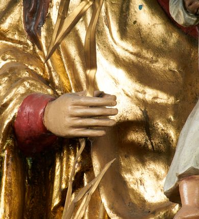 Zdjęcie nr 7: Rzeźba pełnoplastyczna, przyścienna, drążona od tyłu, ustawiona na konsoli. Maria stoi w lekkim kontrapoście, ciężar ciała opierając na lewej nodze, prawą lekko uginając w kolanie. Lewą ręką podtrzymuje siedzące na jej ramieniu Dzieciątko, w prawej ugiętej w łokciu i wysuniętej lekko do przodu trzyma błyskawicę. Twarz pociągła, z długim, prostym, wąskim nosem, oczami o migdałowym wykroju, regularnymi łukami brwiowymi oraz wąskimi ustami, okolona długimi, ciemnobrązowymi włosami, z przedziałkiem pośrodku głowy, opadającymi na ramiona dwoma skręcającymi się w pukle pasmami. Maria ubrana w długą, czerwoną suknię z wąskimi rękawami oraz złoty płaszcz spięty na piersi, przerzucony z przodu przez lewe ramię, układający się pośrodku w trzy płytkie misowe fałdy, po bokach formujący się w dwa festony. Dzieciątko siedzi wyprostowane w ramionach Matki, zwrócone przodem do widza, w prawej rączce trzymając krzyż, w lewej jabłko królewskie. Głowa pochylona lekko na lewe ramię; okrągła twarz z małym, zadartym nosem, wąskimi ustami, niewielkimi oczami i regularnymi łukami brwiowymi, okolona krótkimi ciemnobrązowymi włosami. Jezus ubrany w długą białą szatę układającą się w proste, bardzo płytkie fałdy. Na głowach nowsze korony otwarte.