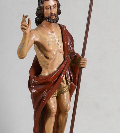 Zdjęcie nr 2: Rzeźba pełna, ustawiona jest na niskiej podstawie w formie płyty oraz na wypukłym postumencie imitującym fragment gruntu. Chrystus ukazany jest w całej postaci, frontalnie, w wykroku, z prawą ręką uniesioną w geście błogosławieństwa, w lewej trzyma drzewce zakończone krzyżem, z brakującą chorągwią. Jego twarz jest szczupła i pociągła, o dużych oczach, prostym nosie i pełnych ustach, okolona krótką, brązową brodą skręconą w dwa pukle oraz brązowymi, silnie kręconymi włosami opadającymi na plecy. Biodra Chrystusa przepasane są krótkim perizonium, zaś na jego lewym ramieniu zawieszony jest czerwony płaszcz, który otacza diagonalnie postać i zarzucony jest z przodu postaci na lewym przedramieniu, odsłaniając tors i nogi. Ciało bardzo wychudzone, o podkreślonych liniach żeber i mostka klatki piersiowej, z zaznaczonymi śladami męki. Polichromia ciała jest naturalistyczna, perizonium pozłacane, a drzewce pomalowane na kolor brązowy.



