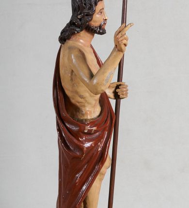 Zdjęcie nr 3: Rzeźba pełna, ustawiona jest na niskiej podstawie w formie płyty oraz na wypukłym postumencie imitującym fragment gruntu. Chrystus ukazany jest w całej postaci, frontalnie, w wykroku, z prawą ręką uniesioną w geście błogosławieństwa, w lewej trzyma drzewce zakończone krzyżem, z brakującą chorągwią. Jego twarz jest szczupła i pociągła, o dużych oczach, prostym nosie i pełnych ustach, okolona krótką, brązową brodą skręconą w dwa pukle oraz brązowymi, silnie kręconymi włosami opadającymi na plecy. Biodra Chrystusa przepasane są krótkim perizonium, zaś na jego lewym ramieniu zawieszony jest czerwony płaszcz, który otacza diagonalnie postać i zarzucony jest z przodu postaci na lewym przedramieniu, odsłaniając tors i nogi. Ciało bardzo wychudzone, o podkreślonych liniach żeber i mostka klatki piersiowej, z zaznaczonymi śladami męki. Polichromia ciała jest naturalistyczna, perizonium pozłacane, a drzewce pomalowane na kolor brązowy.



