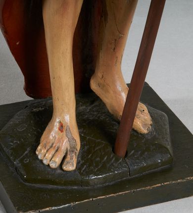 Zdjęcie nr 10: Rzeźba pełna, ustawiona jest na niskiej podstawie w formie płyty oraz na wypukłym postumencie imitującym fragment gruntu. Chrystus ukazany jest w całej postaci, frontalnie, w wykroku, z prawą ręką uniesioną w geście błogosławieństwa, w lewej trzyma drzewce zakończone krzyżem, z brakującą chorągwią. Jego twarz jest szczupła i pociągła, o dużych oczach, prostym nosie i pełnych ustach, okolona krótką, brązową brodą skręconą w dwa pukle oraz brązowymi, silnie kręconymi włosami opadającymi na plecy. Biodra Chrystusa przepasane są krótkim perizonium, zaś na jego lewym ramieniu zawieszony jest czerwony płaszcz, który otacza diagonalnie postać i zarzucony jest z przodu postaci na lewym przedramieniu, odsłaniając tors i nogi. Ciało bardzo wychudzone, o podkreślonych liniach żeber i mostka klatki piersiowej, z zaznaczonymi śladami męki. Polichromia ciała jest naturalistyczna, perizonium pozłacane, a drzewce pomalowane na kolor brązowy.



