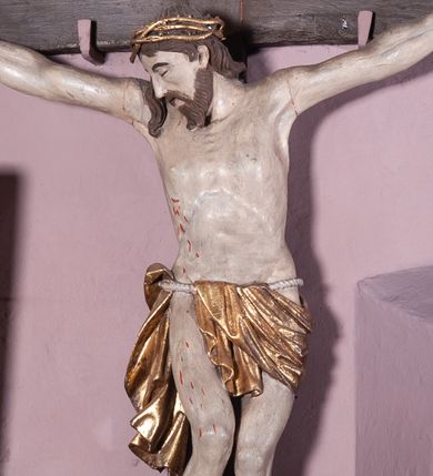 Zdjęcie nr 1: Figura umarłego Chrystusa została przybita do prostego krzyża trzema gwoździami. Jego ciało ukazane jest w lekkim zwisie, o niemal horyzontalnie rozłożonych ramionach, z głową opadającą na prawy bark, z lekko ugiętymi kolanami i stopami skrzyżowanymi w układzie prawa na lewą. Twarz Chrystusa jest szczupła, zwężająca się mocno ku dołowi, z okrągłymi, zamkniętymi oczami, z niewielkim, wąskim nosem i z małymi, rozchylonymi ustami, okolona krótką brązową, brodą, układającą się w dwa pukle oraz brązowymi, kręconym włosami opadającymi na prawe ramię. Ciało Chrystusa jest szczupłe, o delikatnym modelunku, z zaznaczoną muskulaturą ramion i nóg, z wyraźnie zarysowanymi żebrami i mostkiem klatki piersiowej. Perizonium zawieszone na sznurze, częściowo odsłaniające biodra i prawe udo, ze zwisem tkaniny opadającym wzdłuż prawego boku Chrystusa. Na głowie korona cierniowa. Na górnym zakończeniu pionowej belki krzyża kartusz z napisem „I.N.R.I.”. Polichromia karnacji ciała naturalistyczna, z zaznaczonymi śladami męki, tkanina perizonium i korona cierniowa pozłacane. 
