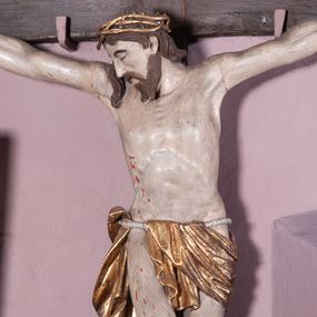 Zdjęcie nr 1: Figura umarłego Chrystusa została przybita do prostego krzyża trzema gwoździami. Jego ciało ukazane jest w lekkim zwisie, o niemal horyzontalnie rozłożonych ramionach, z głową opadającą na prawy bark, z lekko ugiętymi kolanami i stopami skrzyżowanymi w układzie prawa na lewą. Twarz Chrystusa jest szczupła, zwężająca się mocno ku dołowi, z okrągłymi, zamkniętymi oczami, z niewielkim, wąskim nosem i z małymi, rozchylonymi ustami, okolona krótką brązową, brodą, układającą się w dwa pukle oraz brązowymi, kręconym włosami opadającymi na prawe ramię. Ciało Chrystusa jest szczupłe, o delikatnym modelunku, z zaznaczoną muskulaturą ramion i nóg, z wyraźnie zarysowanymi żebrami i mostkiem klatki piersiowej. Perizonium zawieszone na sznurze, częściowo odsłaniające biodra i prawe udo, ze zwisem tkaniny opadającym wzdłuż prawego boku Chrystusa. Na głowie korona cierniowa. Na górnym zakończeniu pionowej belki krzyża kartusz z napisem „I.N.R.I.”. Polichromia karnacji ciała naturalistyczna, z zaznaczonymi śladami męki, tkanina perizonium i korona cierniowa pozłacane. 

