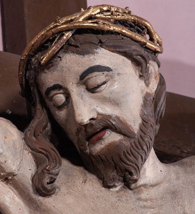 Zdjęcie nr 5: Figura umarłego Chrystusa została przybita do prostego krzyża trzema gwoździami. Jego ciało ukazane jest w lekkim zwisie, o niemal horyzontalnie rozłożonych ramionach, z głową opadającą na prawy bark, z lekko ugiętymi kolanami i stopami skrzyżowanymi w układzie prawa na lewą. Twarz Chrystusa jest szczupła, zwężająca się mocno ku dołowi, z okrągłymi, zamkniętymi oczami, z niewielkim, wąskim nosem i z małymi, rozchylonymi ustami, okolona krótką brązową, brodą, układającą się w dwa pukle oraz brązowymi, kręconym włosami opadającymi na prawe ramię. Ciało Chrystusa jest szczupłe, o delikatnym modelunku, z zaznaczoną muskulaturą ramion i nóg, z wyraźnie zarysowanymi żebrami i mostkiem klatki piersiowej. Perizonium zawieszone na sznurze, częściowo odsłaniające biodra i prawe udo, ze zwisem tkaniny opadającym wzdłuż prawego boku Chrystusa. Na głowie korona cierniowa. Na górnym zakończeniu pionowej belki krzyża kartusz z napisem „I.N.R.I.”. Polichromia karnacji ciała naturalistyczna, z zaznaczonymi śladami męki, tkanina perizonium i korona cierniowa pozłacane. 
