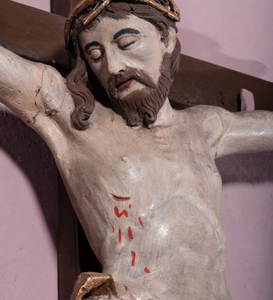 Zdjęcie nr 3: Figura umarłego Chrystusa została przybita do prostego krzyża trzema gwoździami. Jego ciało ukazane jest w lekkim zwisie, o niemal horyzontalnie rozłożonych ramionach, z głową opadającą na prawy bark, z lekko ugiętymi kolanami i stopami skrzyżowanymi w układzie prawa na lewą. Twarz Chrystusa jest szczupła, zwężająca się mocno ku dołowi, z okrągłymi, zamkniętymi oczami, z niewielkim, wąskim nosem i z małymi, rozchylonymi ustami, okolona krótką brązową, brodą, układającą się w dwa pukle oraz brązowymi, kręconym włosami opadającymi na prawe ramię. Ciało Chrystusa jest szczupłe, o delikatnym modelunku, z zaznaczoną muskulaturą ramion i nóg, z wyraźnie zarysowanymi żebrami i mostkiem klatki piersiowej. Perizonium zawieszone na sznurze, częściowo odsłaniające biodra i prawe udo, ze zwisem tkaniny opadającym wzdłuż prawego boku Chrystusa. Na głowie korona cierniowa. Na górnym zakończeniu pionowej belki krzyża kartusz z napisem „I.N.R.I.”. Polichromia karnacji ciała naturalistyczna, z zaznaczonymi śladami męki, tkanina perizonium i korona cierniowa pozłacane. 
