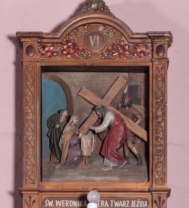 Zdjęcie nr 10: Stacje Drogi krzyżowej w kształcie stojących prostokątów zostały ujęte architektoniczną ramą. Obrazy ustawiono na cokole, po bokach są flankowane dwoma pilastrami, podtrzymującymi wyłamane belkowanie, zamknięte gzymsem w kształcie łuku nadwieszonego. Na szczycie, w rzeźbionych owocach winogron osadzono grecki krzyżyk o trójlistnie zakończonych ramionach z uskokami. Pilastry są zdobione symetryczną wicią cierniową, a pole zwieńczenia bogato dekorowane wicią roślinną złożoną z bujnych, czerwonych kwiatów otaczających numer stacji umieszczony w owalu na tle krzyżyka greckiego. 
Sceny przeważnie wielopostaciowe, płaskorzeźbione, barwnie polichromowane. Postacie o poprawnej anatomii ciała, poruszone, na pierwszym planie bardziej wypukłe. Tło błękitne, malowane. W partii cokołu umieszczono malowane tytuły stacji:
I. „JEZUS NA ŚMIERĆ OSĄDZONY.”
II. „JEZUS BIERZE KRZYŻ NA RAMIONA.”
III. „JEZUS PIERWSZY RAZ UPADA.”
IV. „JEZUS SPOTYKA NAJŚW(IĘTSZĄ) MATKĘ SWOJĄ”
V. „SZYMON CYR(ENEJCZYK) POMAGA NIEŚĆ KRZYŻ JEZUSA”
VI. „ŚW(IĘTA) WERONIKA OCIERA TWARZ JEZUSA”
VII. „JEZUS DRUGI RAZ UPADA”
VIII. „JEZUS NAPOTYKA PŁACZĄCE NIEWIASTY”
IX. „JEZUS TRZECI RAZ UPADA.”
X. „JEZUS Z SZAT OBNAŻONY”
XI. „JEZUS DO KRZYŻA PRZYBITY”
XII. „JEZUS NA KRZYŻU UMIERA.”
XIII. „JEZUS Z KRZYŻA ZDJĘTY.”
XIV. „JEZUS DO GROBU ZŁOŻONY.”
