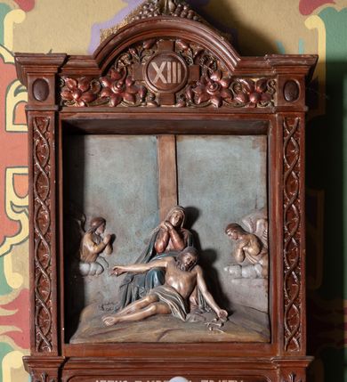 Zdjęcie nr 5: Stacje Drogi krzyżowej w kształcie stojących prostokątów zostały ujęte architektoniczną ramą. Obrazy ustawiono na cokole, po bokach są flankowane dwoma pilastrami, podtrzymującymi wyłamane belkowanie, zamknięte gzymsem w kształcie łuku nadwieszonego. Na szczycie, w rzeźbionych owocach winogron osadzono grecki krzyżyk o trójlistnie zakończonych ramionach z uskokami. Pilastry są zdobione symetryczną wicią cierniową, a pole zwieńczenia bogato dekorowane wicią roślinną złożoną z bujnych, czerwonych kwiatów otaczających numer stacji umieszczony w owalu na tle krzyżyka greckiego. 
Sceny przeważnie wielopostaciowe, płaskorzeźbione, barwnie polichromowane. Postacie o poprawnej anatomii ciała, poruszone, na pierwszym planie bardziej wypukłe. Tło błękitne, malowane. W partii cokołu umieszczono malowane tytuły stacji:
I. „JEZUS NA ŚMIERĆ OSĄDZONY.”
II. „JEZUS BIERZE KRZYŻ NA RAMIONA.”
III. „JEZUS PIERWSZY RAZ UPADA.”
IV. „JEZUS SPOTYKA NAJŚW(IĘTSZĄ) MATKĘ SWOJĄ”
V. „SZYMON CYR(ENEJCZYK) POMAGA NIEŚĆ KRZYŻ JEZUSA”
VI. „ŚW(IĘTA) WERONIKA OCIERA TWARZ JEZUSA”
VII. „JEZUS DRUGI RAZ UPADA”
VIII. „JEZUS NAPOTYKA PŁACZĄCE NIEWIASTY”
IX. „JEZUS TRZECI RAZ UPADA.”
X. „JEZUS Z SZAT OBNAŻONY”
XI. „JEZUS DO KRZYŻA PRZYBITY”
XII. „JEZUS NA KRZYŻU UMIERA.”
XIII. „JEZUS Z KRZYŻA ZDJĘTY.”
XIV. „JEZUS DO GROBU ZŁOŻONY.”
