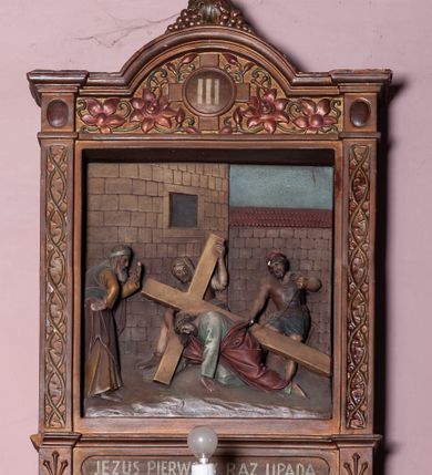 Zdjęcie nr 7: Stacje Drogi krzyżowej w kształcie stojących prostokątów zostały ujęte architektoniczną ramą. Obrazy ustawiono na cokole, po bokach są flankowane dwoma pilastrami, podtrzymującymi wyłamane belkowanie, zamknięte gzymsem w kształcie łuku nadwieszonego. Na szczycie, w rzeźbionych owocach winogron osadzono grecki krzyżyk o trójlistnie zakończonych ramionach z uskokami. Pilastry są zdobione symetryczną wicią cierniową, a pole zwieńczenia bogato dekorowane wicią roślinną złożoną z bujnych, czerwonych kwiatów otaczających numer stacji umieszczony w owalu na tle krzyżyka greckiego. 
Sceny przeważnie wielopostaciowe, płaskorzeźbione, barwnie polichromowane. Postacie o poprawnej anatomii ciała, poruszone, na pierwszym planie bardziej wypukłe. Tło błękitne, malowane. W partii cokołu umieszczono malowane tytuły stacji:
I. „JEZUS NA ŚMIERĆ OSĄDZONY.”
II. „JEZUS BIERZE KRZYŻ NA RAMIONA.”
III. „JEZUS PIERWSZY RAZ UPADA.”
IV. „JEZUS SPOTYKA NAJŚW(IĘTSZĄ) MATKĘ SWOJĄ”
V. „SZYMON CYR(ENEJCZYK) POMAGA NIEŚĆ KRZYŻ JEZUSA”
VI. „ŚW(IĘTA) WERONIKA OCIERA TWARZ JEZUSA”
VII. „JEZUS DRUGI RAZ UPADA”
VIII. „JEZUS NAPOTYKA PŁACZĄCE NIEWIASTY”
IX. „JEZUS TRZECI RAZ UPADA.”
X. „JEZUS Z SZAT OBNAŻONY”
XI. „JEZUS DO KRZYŻA PRZYBITY”
XII. „JEZUS NA KRZYŻU UMIERA.”
XIII. „JEZUS Z KRZYŻA ZDJĘTY.”
XIV. „JEZUS DO GROBU ZŁOŻONY.”

